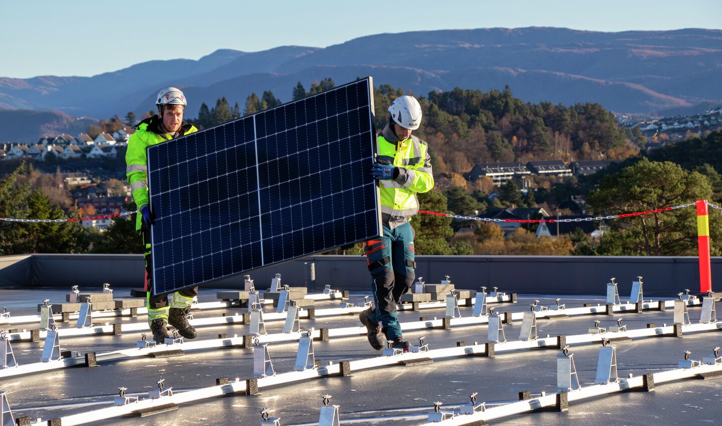 Et solcellepanel bæres på plass på taket til Møllers Eiendom i Kokstadvegen 29 i Bergen.