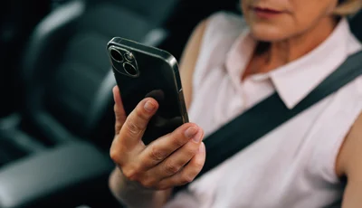 Kvinna i bil tittar på sin mobil.