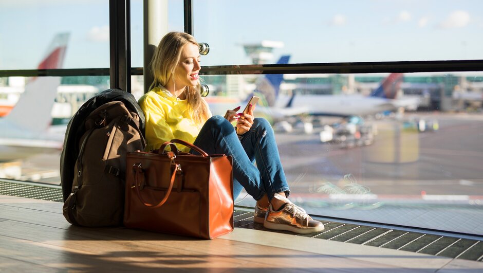 Nainen istuu lentokentällä laukkujensa kanssa