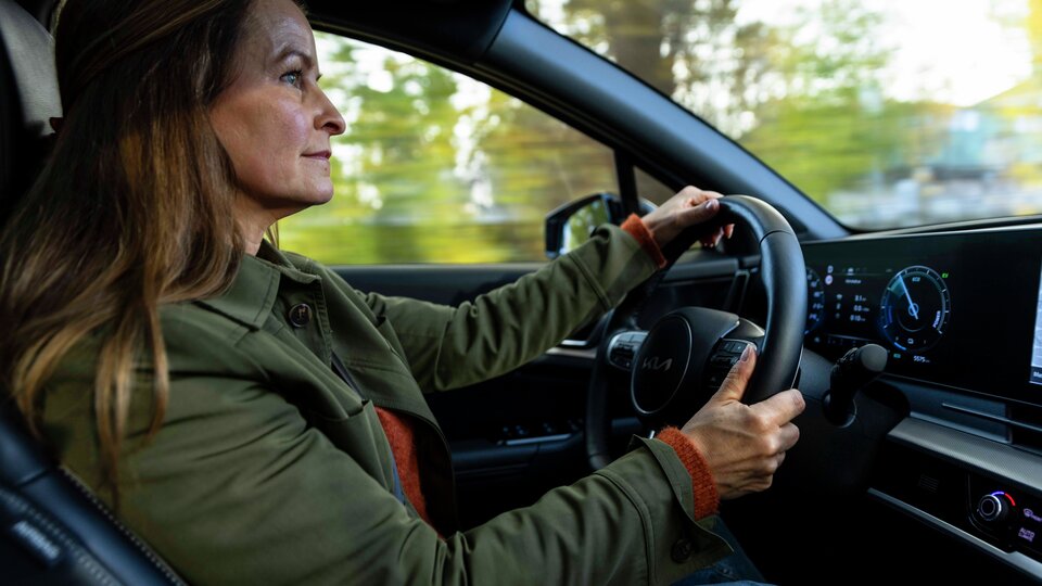 Kvinna håller båda händerna på ratten när hon kör bil.