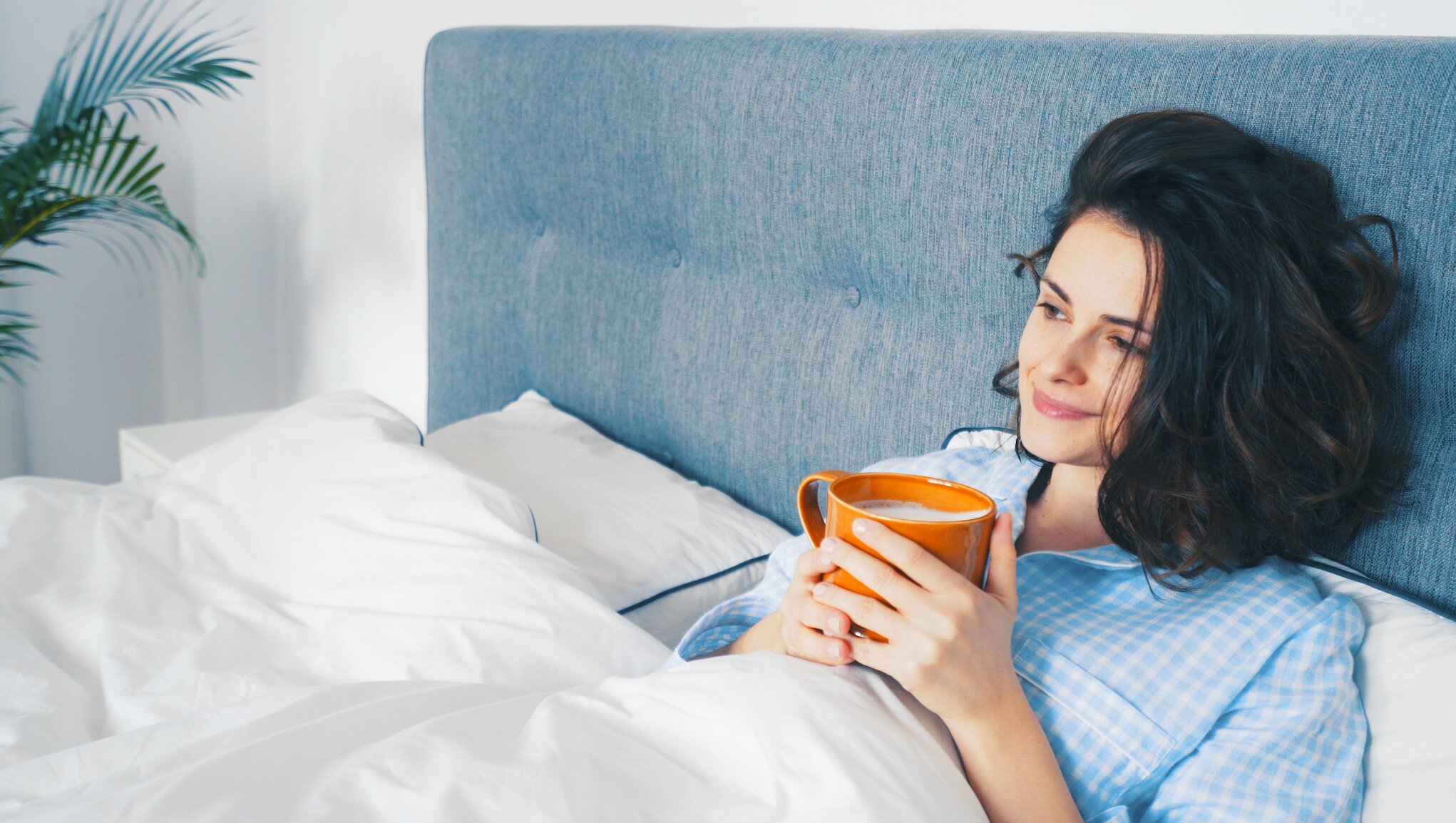 Kvinna dricker te i sängen
