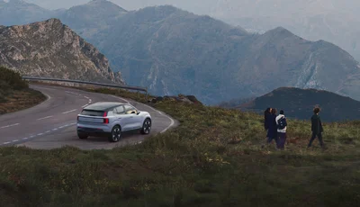 Volvo EX30 parkerad vid en väg omgiven av berg.