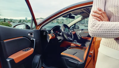 Kvinna ståendes framför orange bil med öppen dörr