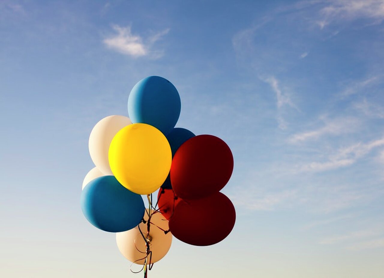 Colorful balloons on a string against a blue sky. Original public domain image from Wikimedia Commons