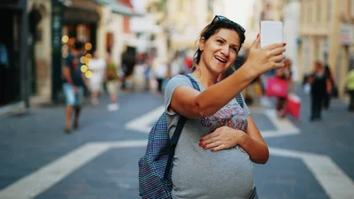 Nainen ottaa selfietä puhelimella matkakohteen kadulla