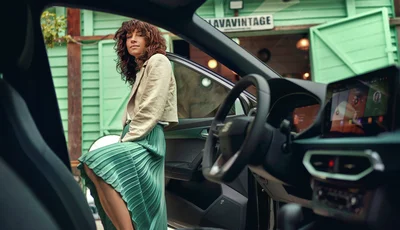 Kvinna med gröna kläder kollar in i en bils kupé