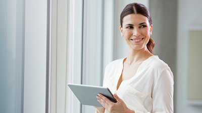 person smiling with tablet computer in hand.
