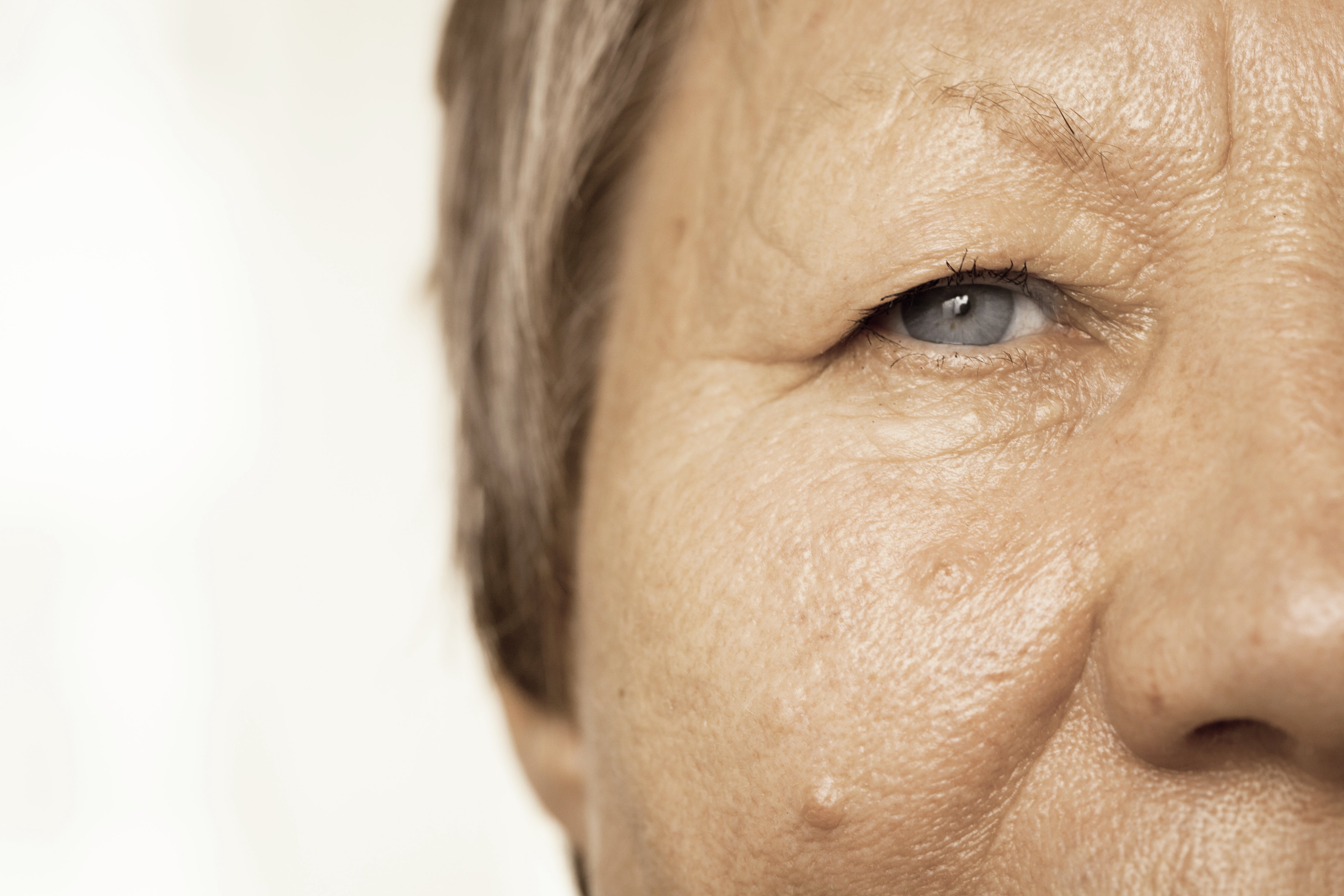 Details of senior woman half face. Elderly pensioner female, cheek and eye close up.