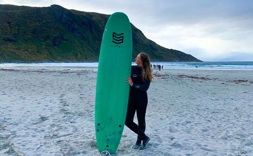 Ida med surfbrettet på stranda i Hoddevik