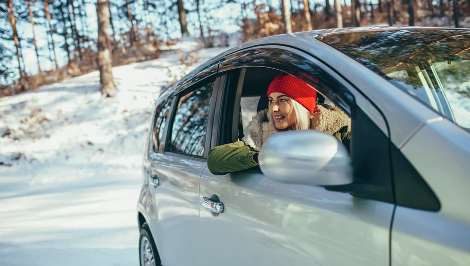 Kvinde kigger ud af vinduet i en bil i snedækket terræn