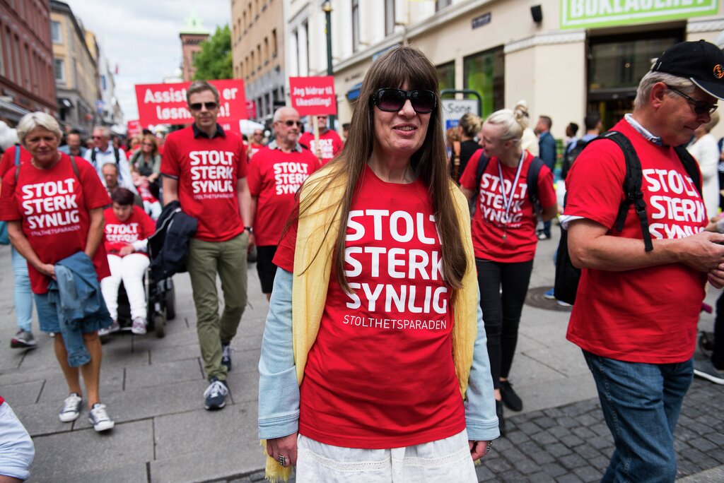 Berit Vegheim i Stolthetsparaden i 2016. Det året fikk Stopp diskrimineringen Stolthetsprisen. Hun har langt brunt hår, solbriller og en rød t-skjorte med teksten "Stolt, sterk, synlig!". 