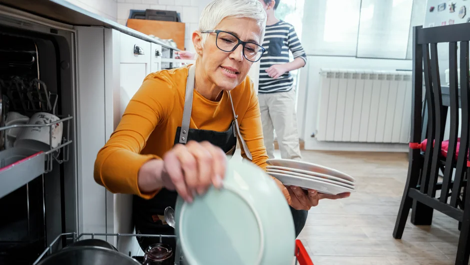 En kvinne rydder ut av en oppvaskmaskin