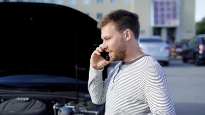 Man talar i mobiltelefon framför en bil