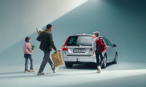 Familj med packning går mot en Volvo V70.