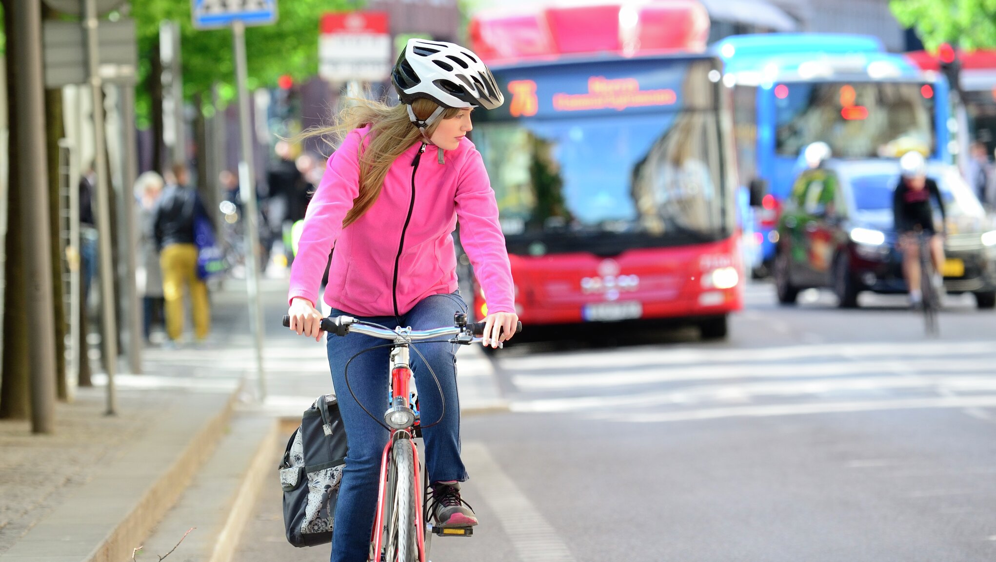 kvinna med rosa jacka cyklar i trafiken