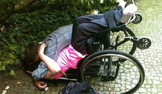 Ihra-Lill Scharning klemmer en person mens hun ligger i veltet rullestol på brostein