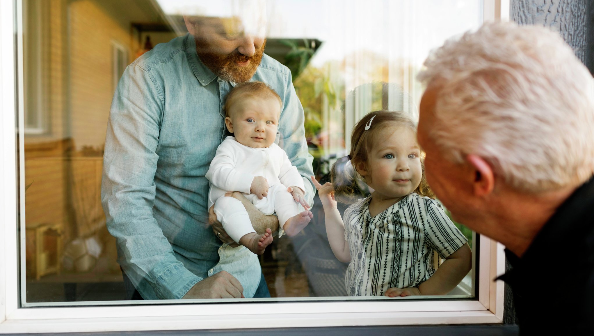 Bestefar hilser på barnebarna og familien i vinduet.