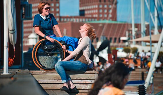 Kvinne i rullestol med assistent foran Oslo rådhus