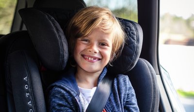 Leende pojke sitter i framåtvänd bilbarnstol