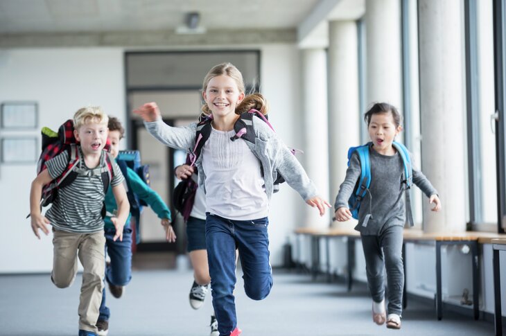 Barn springer i korridor. Illustrerer elever, skole, glede, skolehverdag, friminutt, kjønn, gutt, jente, ransel.