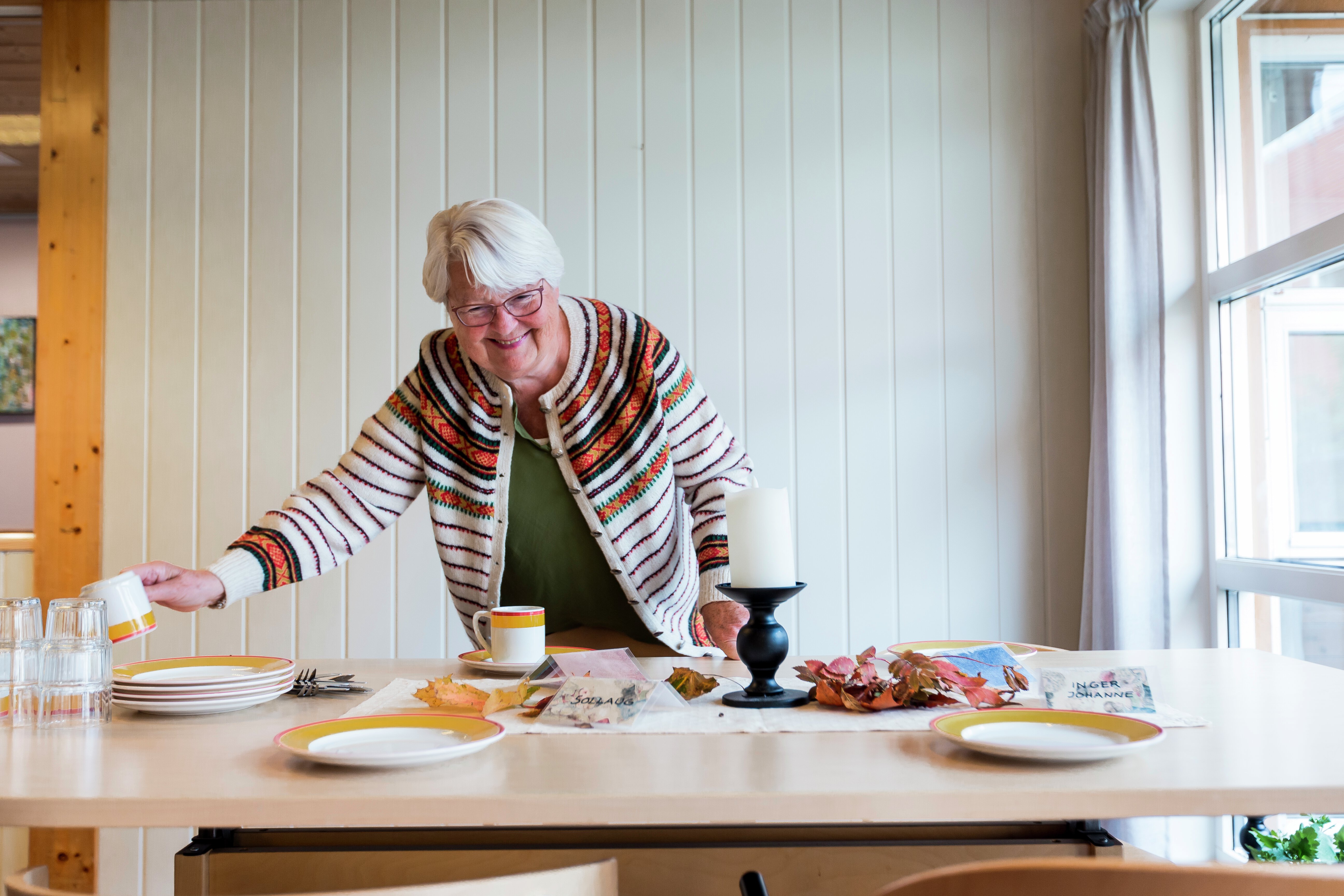 Eldre kvinne bak bord med mat. Foto
