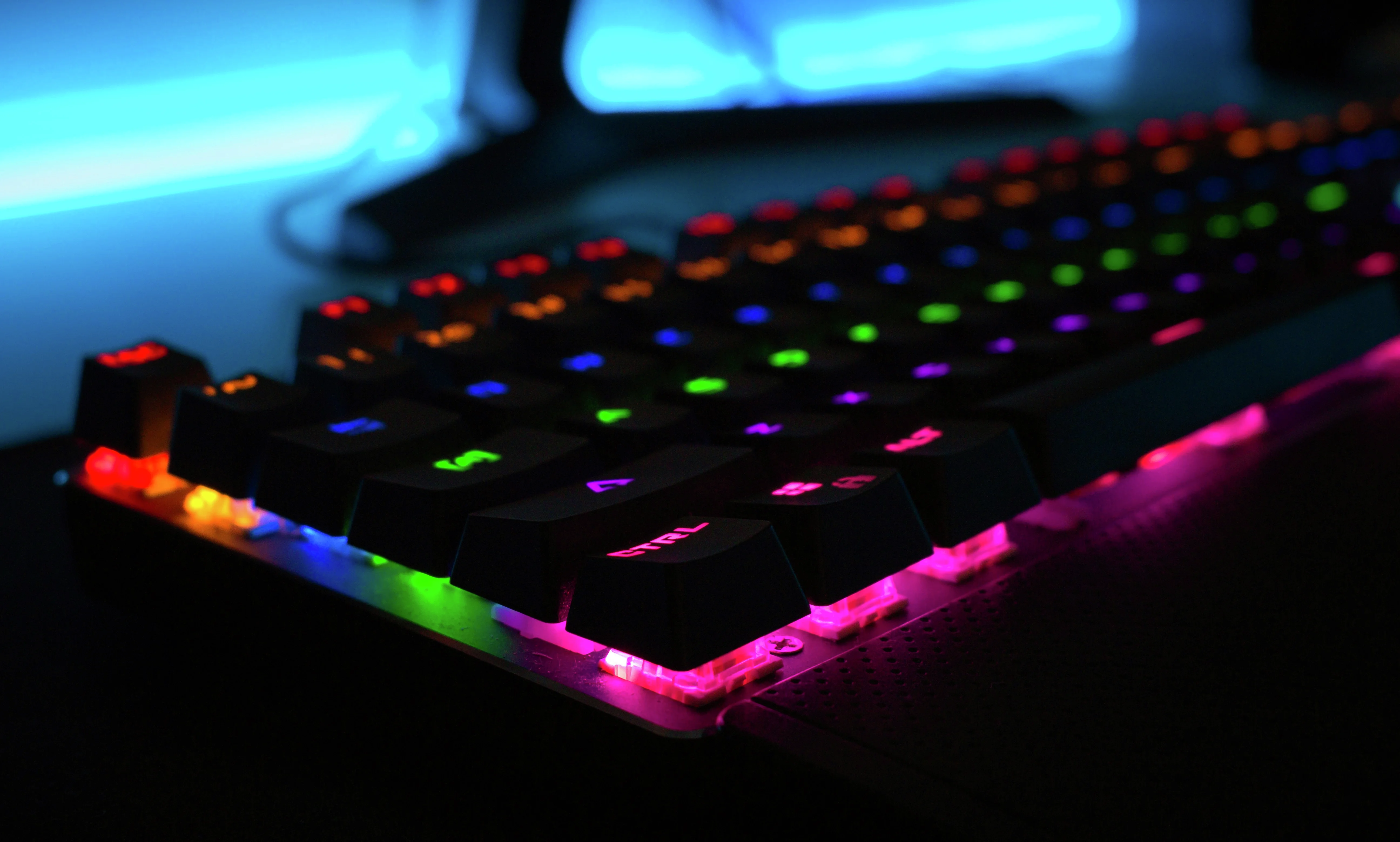 Et mekanisk spilltastatur med levende RGB-regnbuefargede bakgrunnsbelysning som lyser i et mørkt rom.
