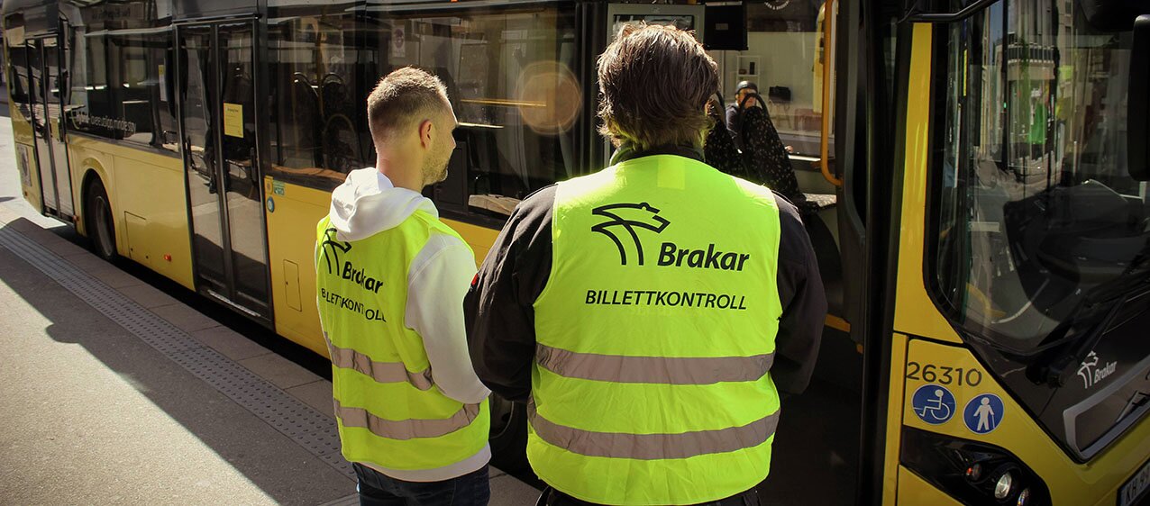 Bilde av billettkontrollører foran en buss.