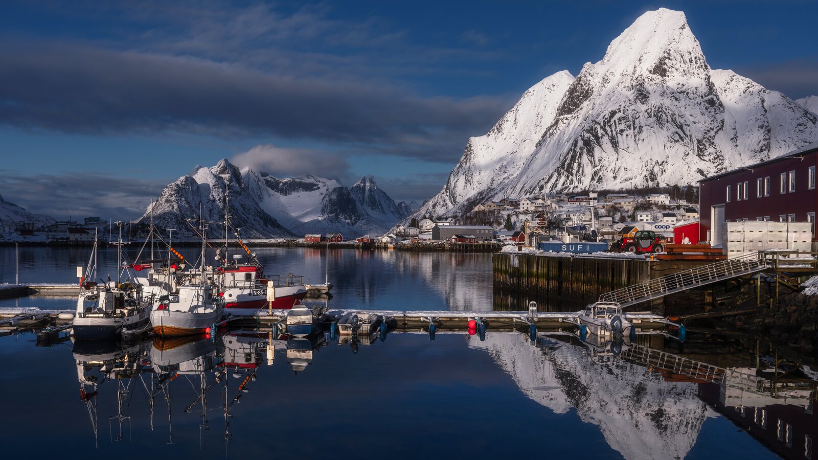 Havn i Lofoten med fiskebåter og snødekte fjell