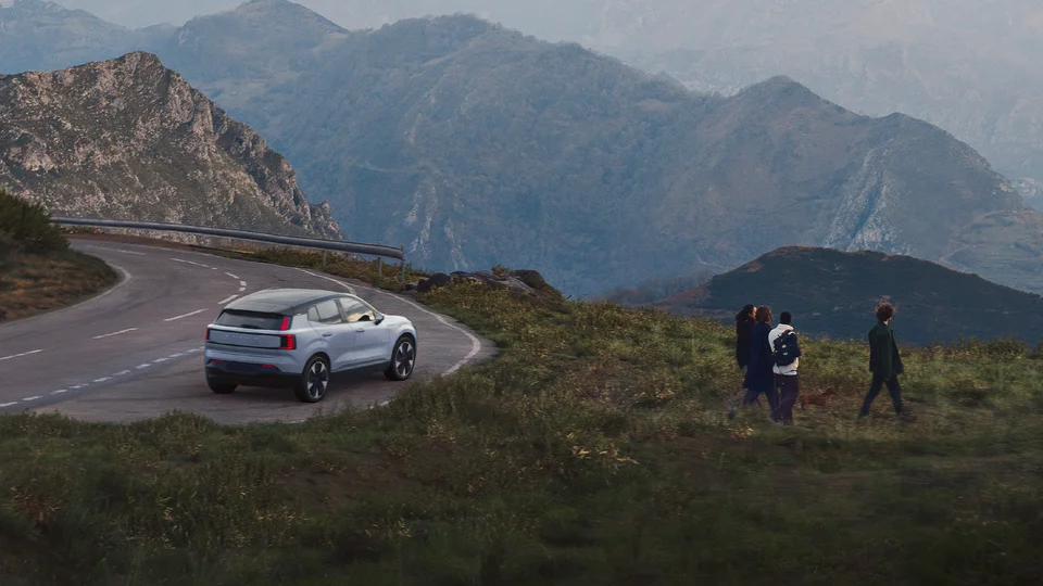 Volvo EX30 parkerad vid en väg omgiven av berg.