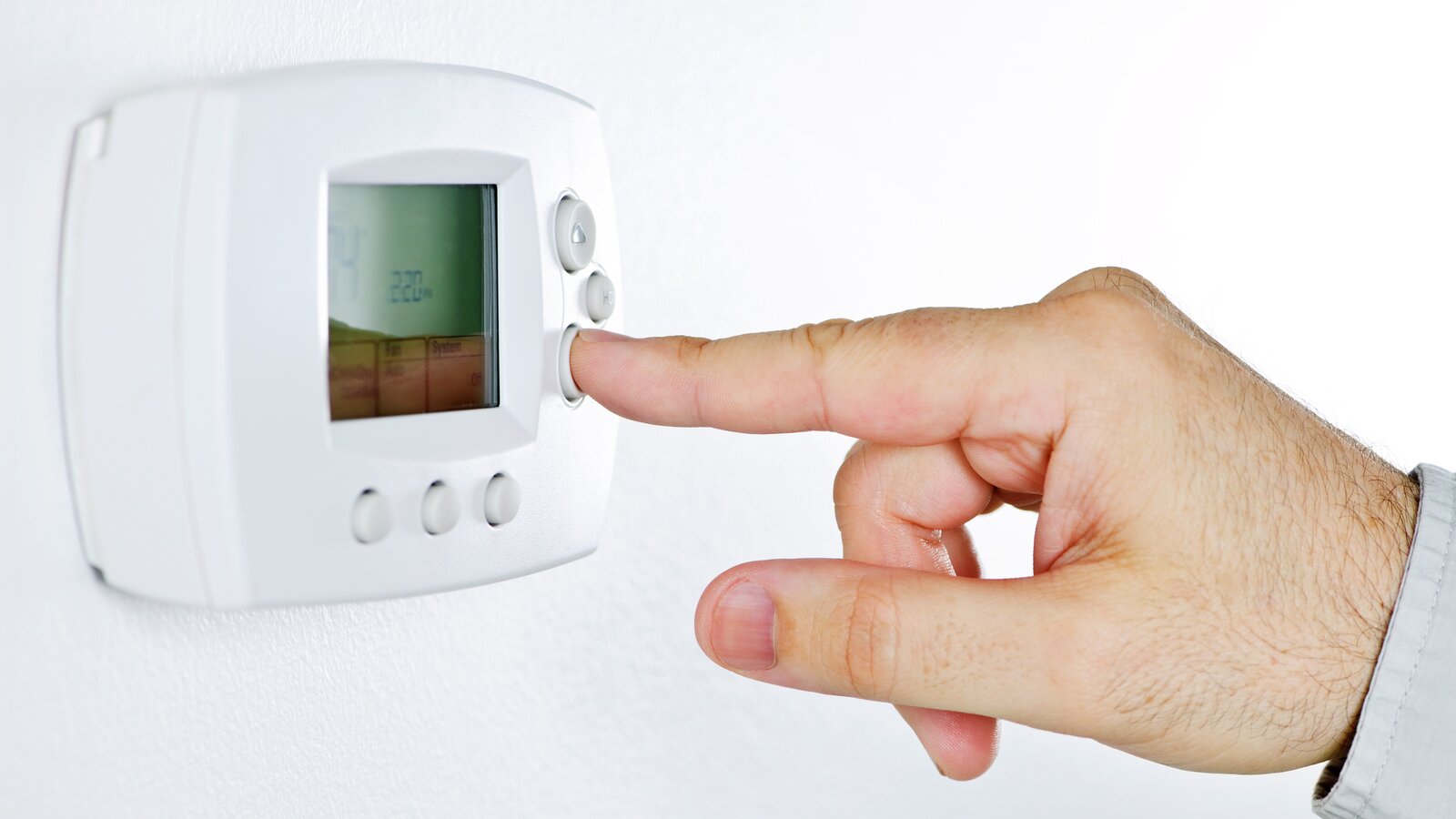 Person justerer temperaturen på en termostat