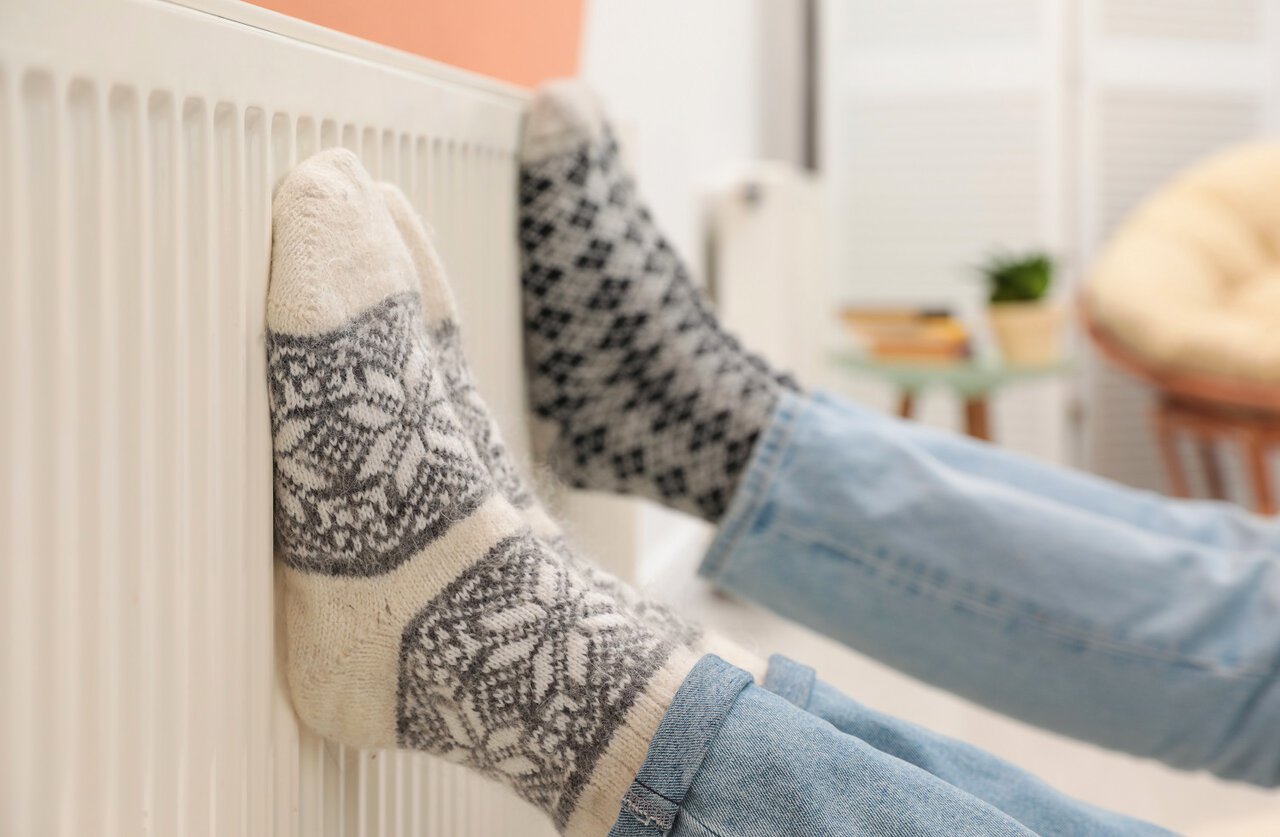 Føtter med ullsokker som varmer seg på radiator