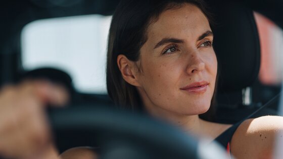 Nainen katsoo mietteliäänä auton ratissa