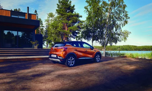 Orange Renault står parkerad i naturmiljö