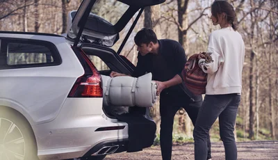 Par lastar in packning i bagageutrymmet på en Volvo V60.