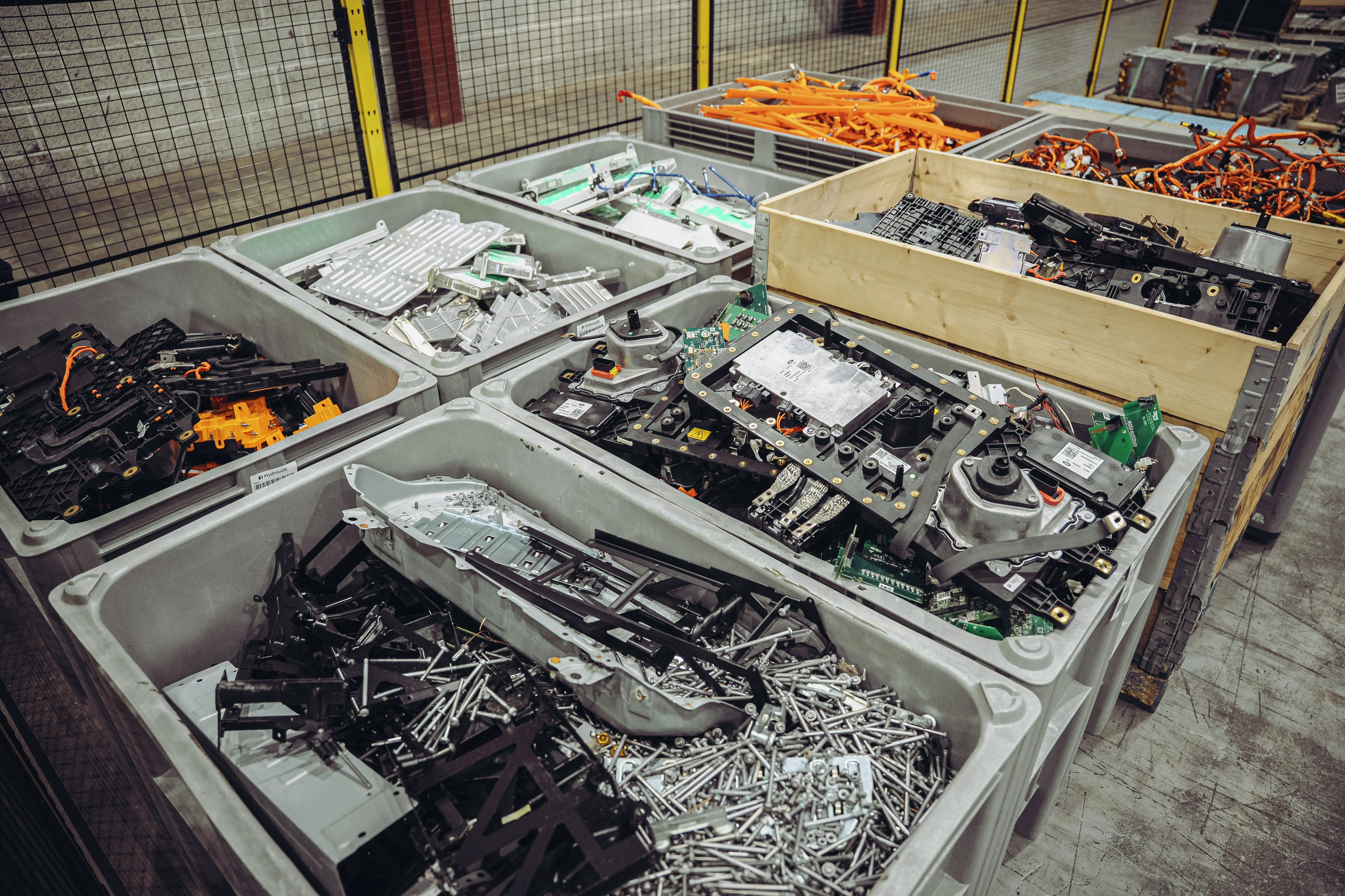 Beholdere fylt med diverse elektroniske komponenter, kretskort og metalldeler i et resirkuleringsanlegg for e-avfall eller sorteringsområde.