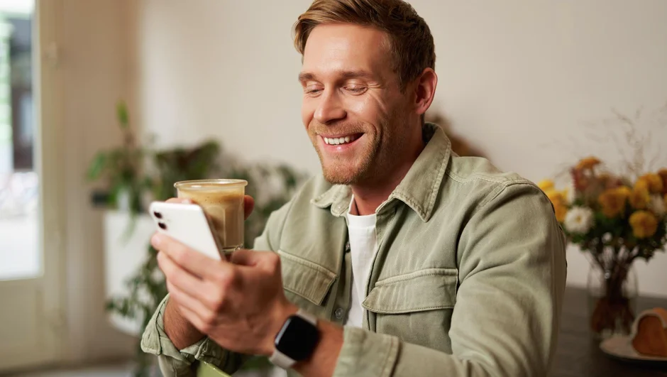 Mand sidder i sit hus og kigger på sin mobil