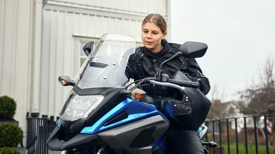 Kvinne sitter på en parkert motorsykkel