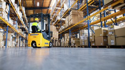 person driving fork lift in a warehouse.