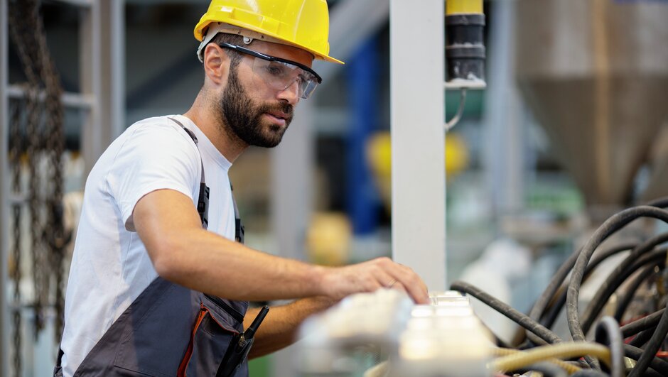 man wearing a helmet, working in a factory.