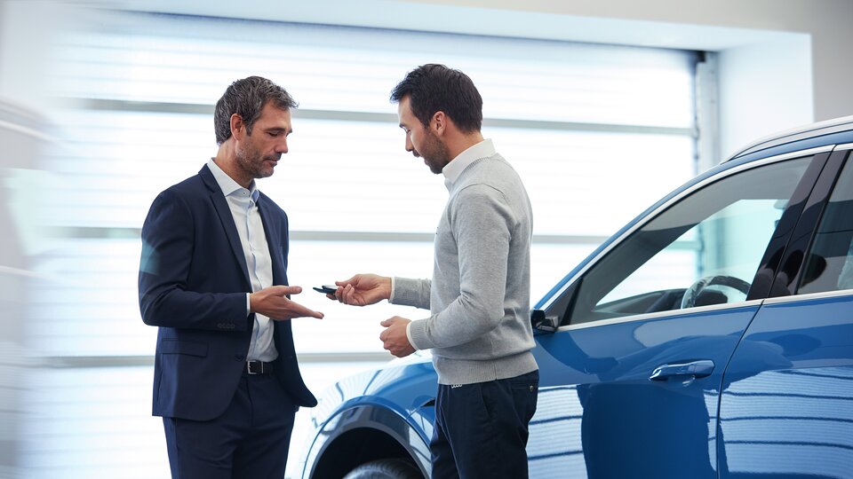 Bilhandlare överlämnar bilnycklar till den nya ägaren.