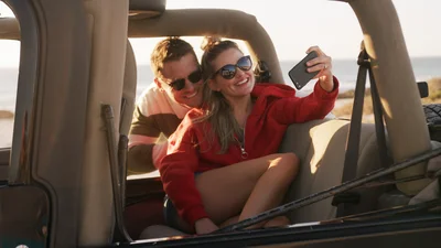Nainen ja mies ottavat selfien autossaan