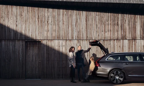 Familie står bak Volvo V90 med åpent bagasjerom