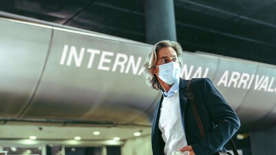 man at the airport wearing a surgical mask.
