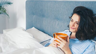 Kvinna dricker te i sängen