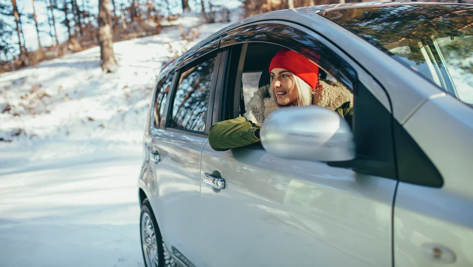 Kvinde sidder i en bil der kører i sne