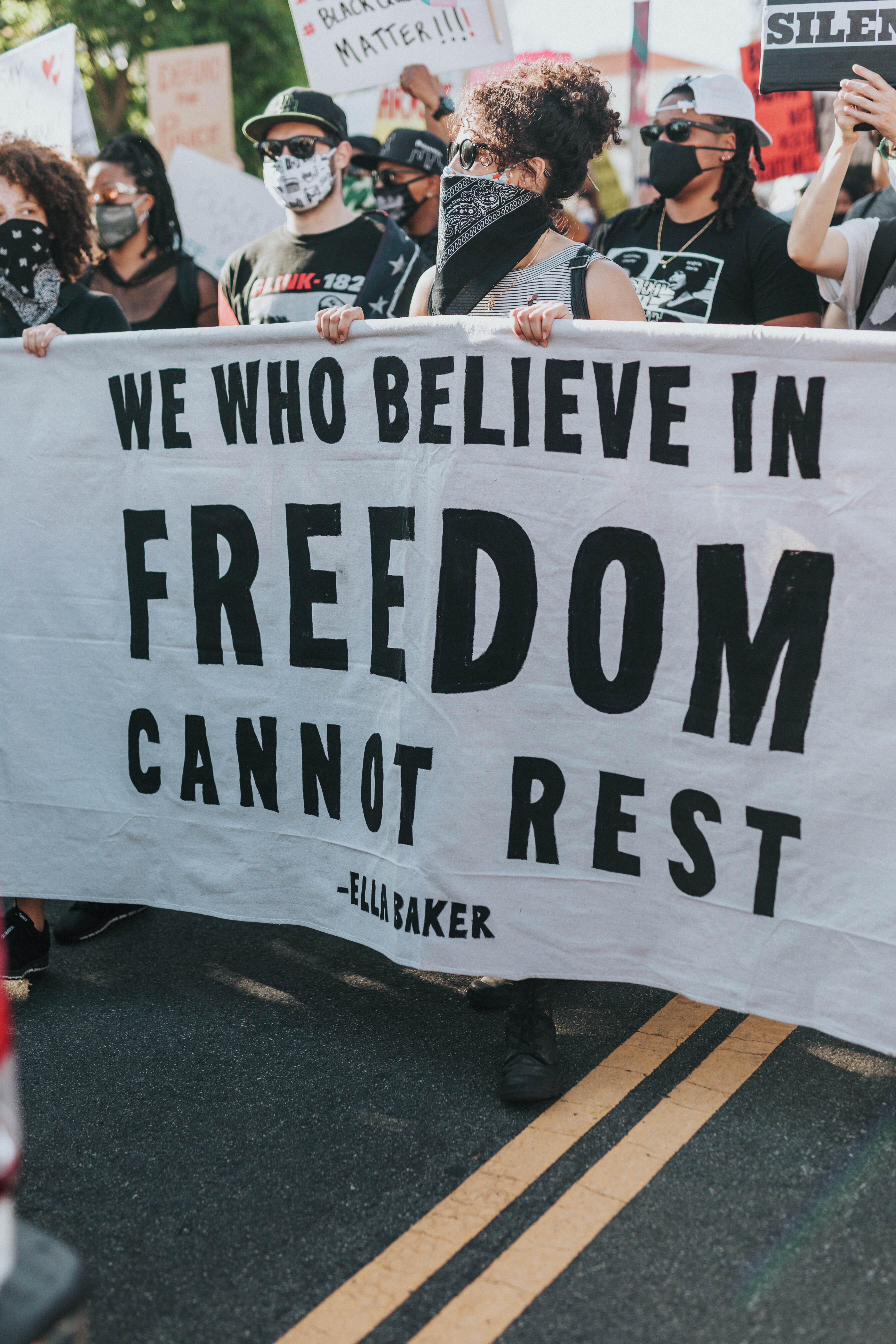 Mennesker med ulik etnisk opprinnelse i demonstrasjonstog med en stor parole der det står "We who believe in freedom cannot rest".