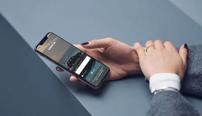 Hand håller i en smartphone med Volvia-appen.