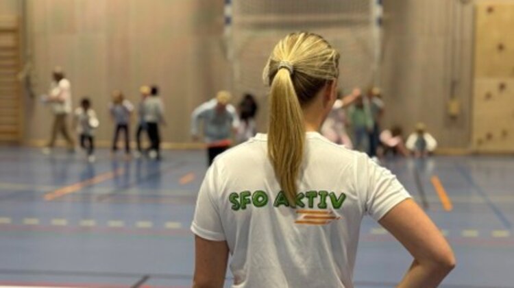 Kvinne med SFO Aktiv på t-skjorta i en idrettshall