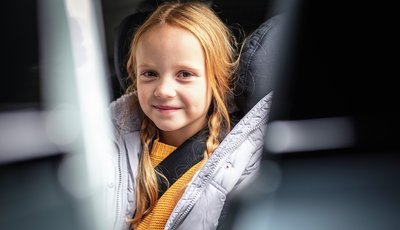 Flicka med vinterkläder sitter i framåtvänd bilbarnstol