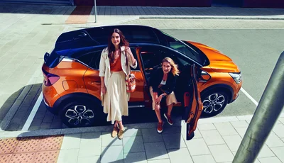 Två kvinnor framför orange Renault